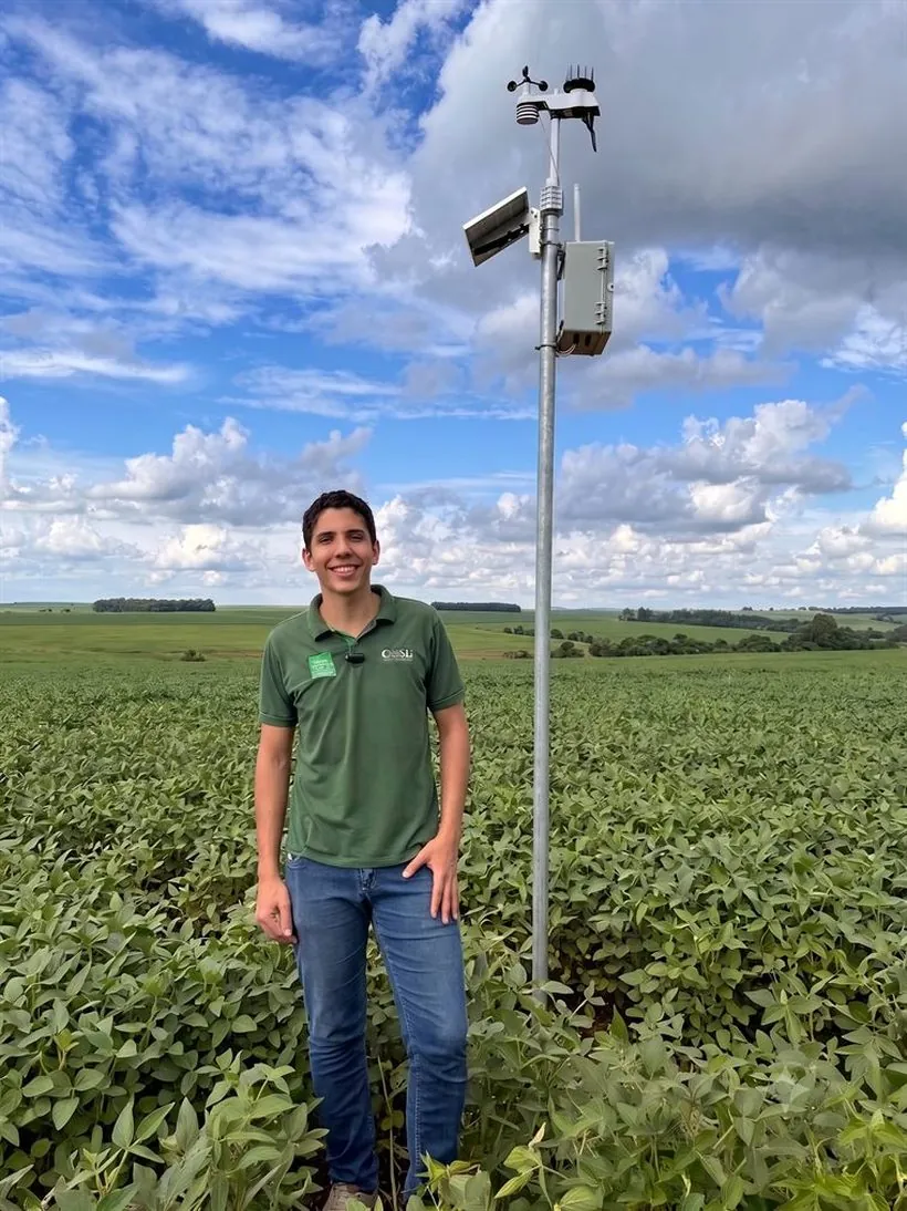 Técnico da S2D ao lado da estação meteorológica SenseBox Climate instalada no meio da lavoura de soja.